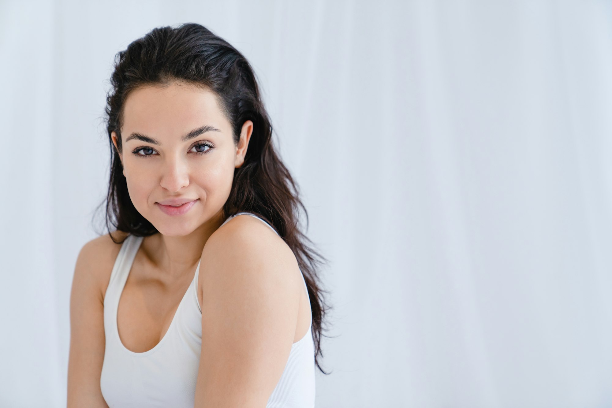 Young pretty girl with clear skin sitting on the bed in sleeping clothes